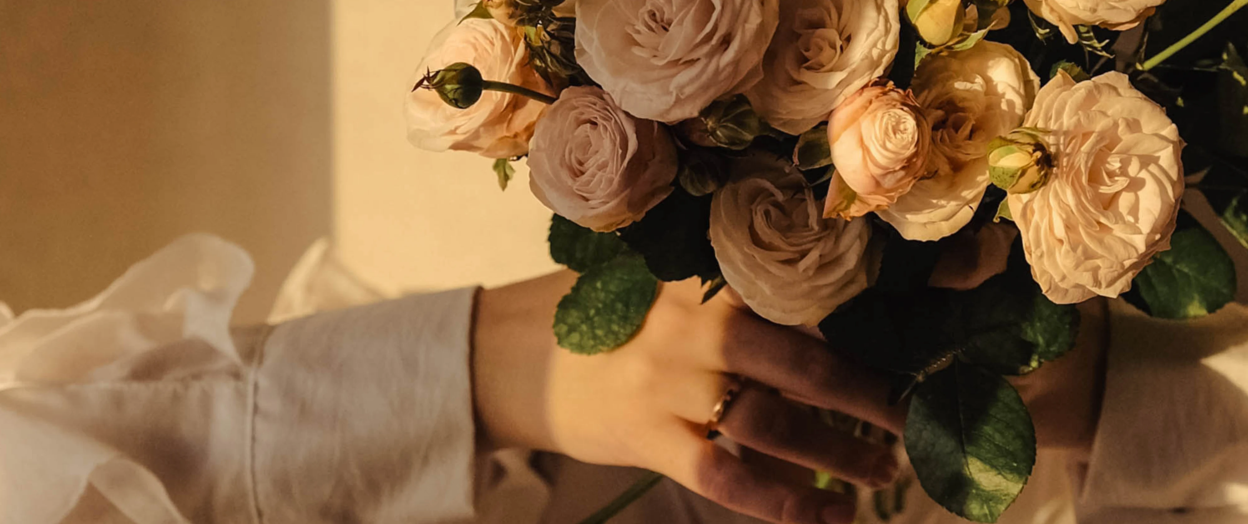 Woman holding a bouquet of pale roses in warm light