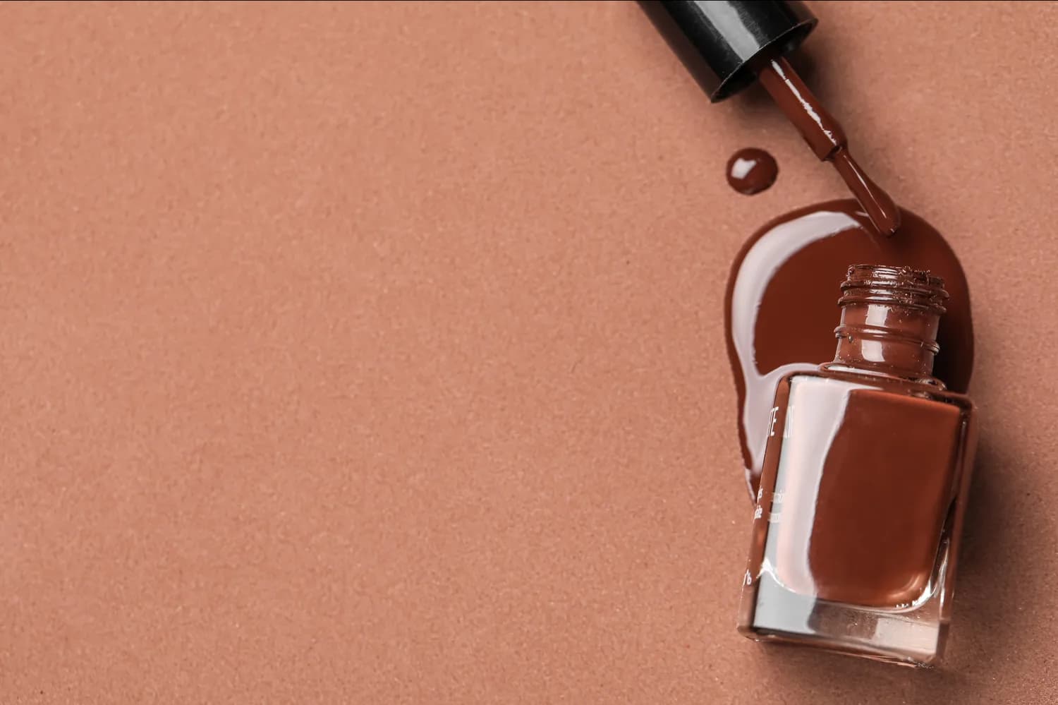 Brown nail polish bottle and spill on a warm background