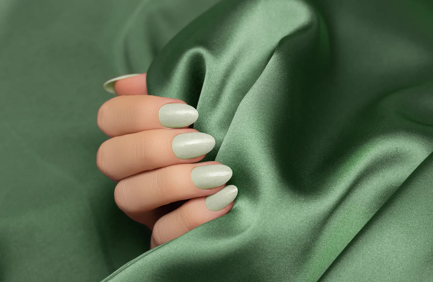 Sage green manicure on emerald silk